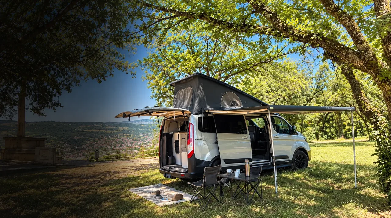 Le van aménagé Ford Nugget Westfalia A'Van-ture en bivouac sous un arbre, toit relevé et auvent déployé, face au panorama d'une vallée du Lot