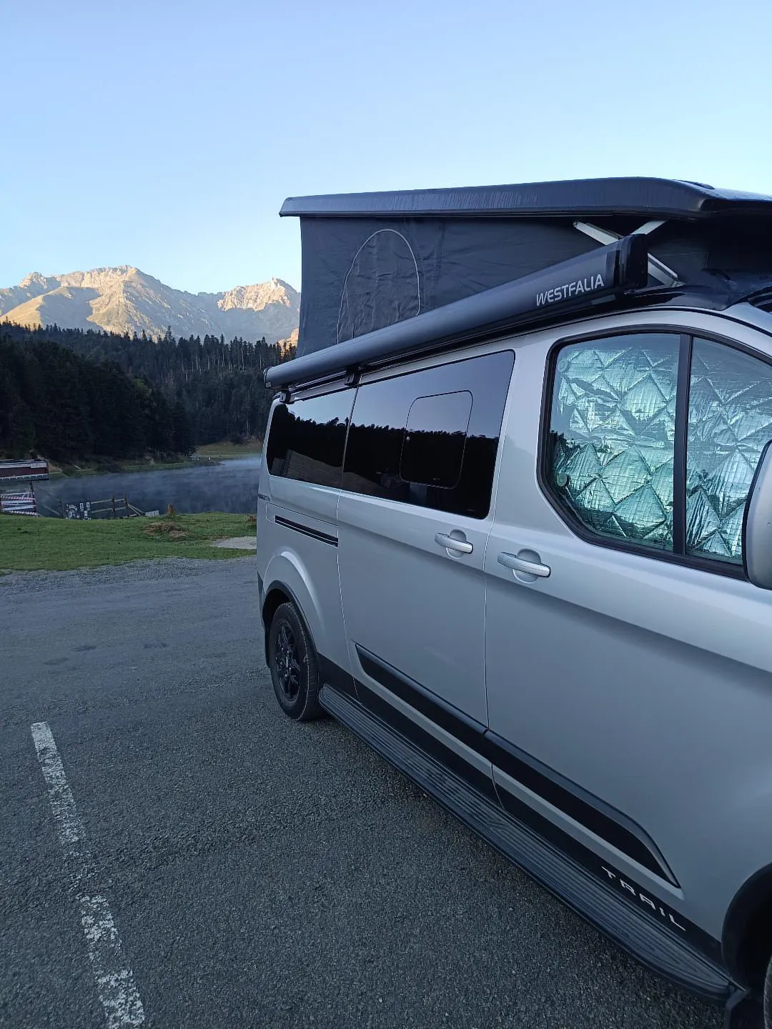 Van A'Van-ture toit relevé au bord d'un lac de montagne à la lumière dorée